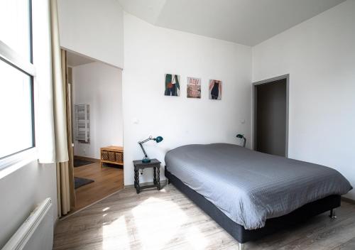 een slaapkamer met een bed en een lamp op een tafel bij Le Loft Horloger avec parking in Besançon