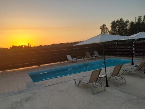 a pool with chairs and umbrellas and a sunset at Sunset Villa in Nea Paphos