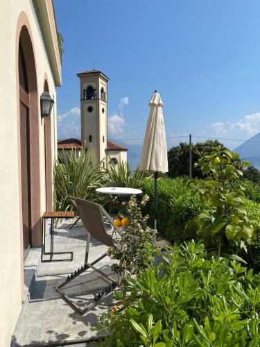 a patio with a table and an umbrella and a clock tower at Villa Rubino Apartment con giardino e jacuzzi vista lago in Stresa