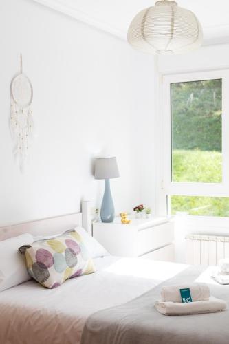 a white bedroom with a bed and a window at Sabea - Baskey Rentals in Iraeta