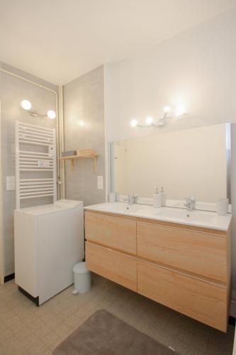 une salle de bain avec deux lavabos, une baignoire et un miroir dans l'établissement Coquet appartement Type 2 de 56 m² en centre ville, à Briançon