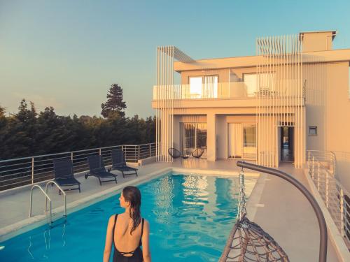 a woman standing in front of a swimming pool at IO Luxury Pool & Hot Tub Suites in Preveza