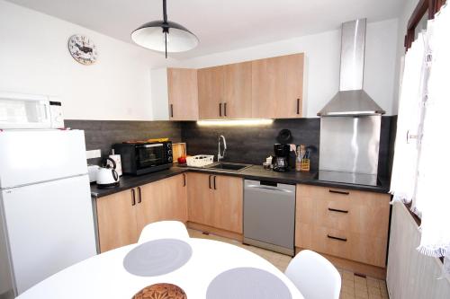 a kitchen with wooden cabinets and a white refrigerator at Coquet appartement Type 2 de 56 m² en centre ville in Briançon