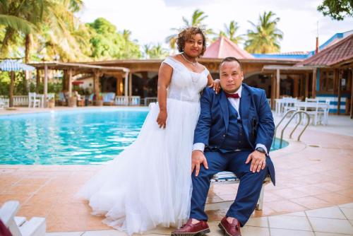 a bride and groom sitting next to a pool at Victory Hotel & Restaurant Tulear in Toliara