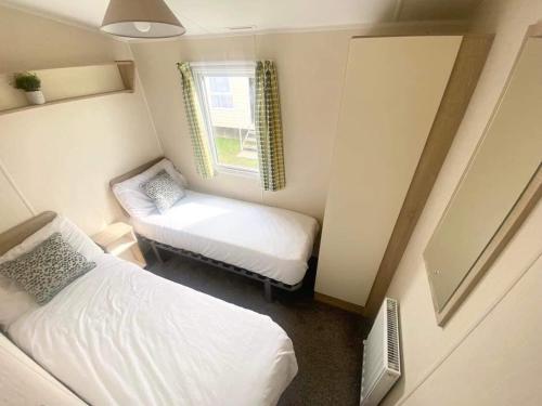 a small room with two beds and a window at CW77 St Osyth Beach Holiday Park in Saint Osyth
