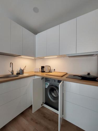a kitchen with white cabinets and a washing machine at Preilos39 in Preila