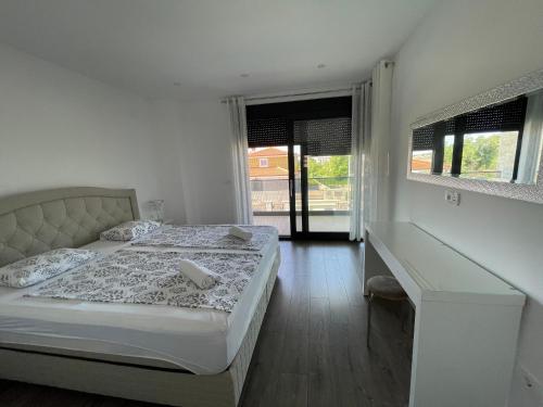 a white bedroom with two beds and a desk at Vila Softic Azra in Umag
