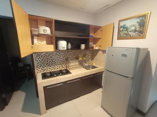 a small kitchen with a refrigerator and a sink at Apartment Thamrin City mall 3 BR near Tanah abang in Jakarta