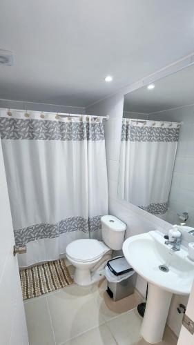 a white bathroom with a toilet and a sink at Hermoso y Tranquilo Departamento / Parquemar 3 in El Tabo