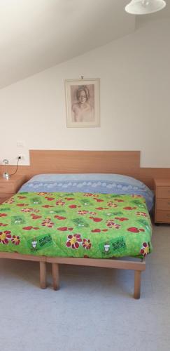 Una cama con una manta verde con flores. en Le Acacie rooms - ex B&B, en Termoli