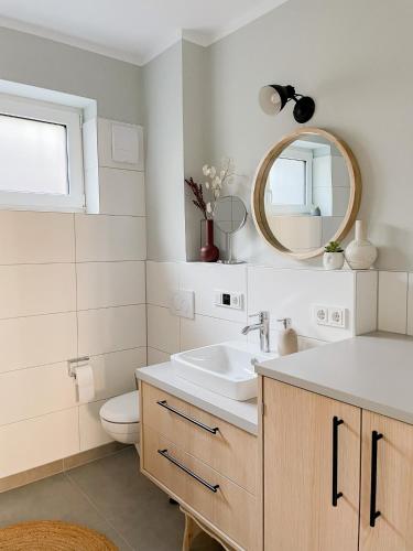 a bathroom with a sink and a toilet and a mirror at Ferienwohnung Swedish Summer in Scharbeutz