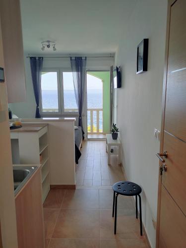 a kitchen with a table and a stool in a room at Apartments Blueness in Prigradica