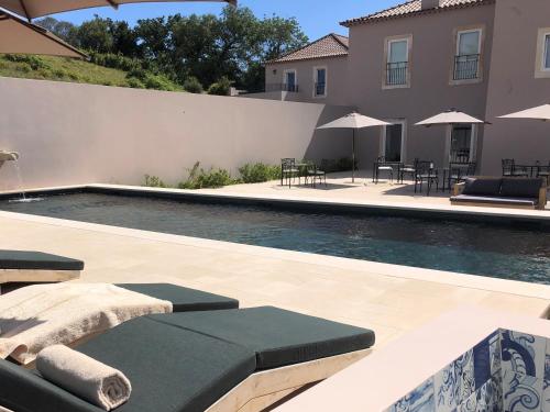 a pool with chairs and umbrellas next to a house at Quinta do Porto Nogueira in Alguber