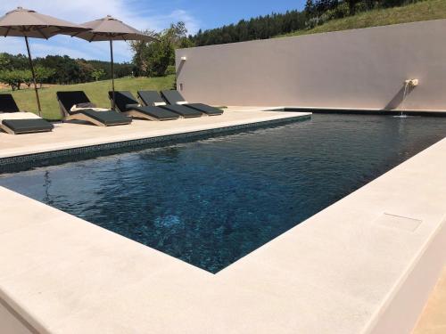 an infinity pool with chairs and an umbrella at Quinta do Porto Nogueira in Alguber