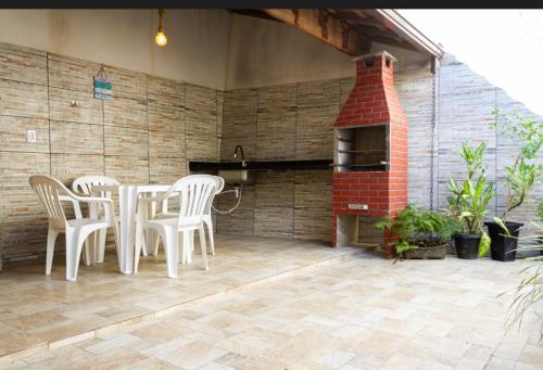 d'une terrasse avec une table, des chaises et un four en briques. dans l'établissement Aconchego Premium, à Angra dos Reis