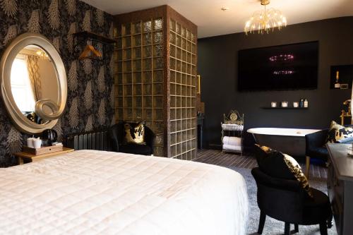 a bedroom with a bed and a mirror and a tub at All Seasons Boutique Hotels in Filey