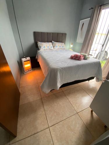 1 dormitorio con cama, ventana y lámpara en Apartamento el uno, en Chuy