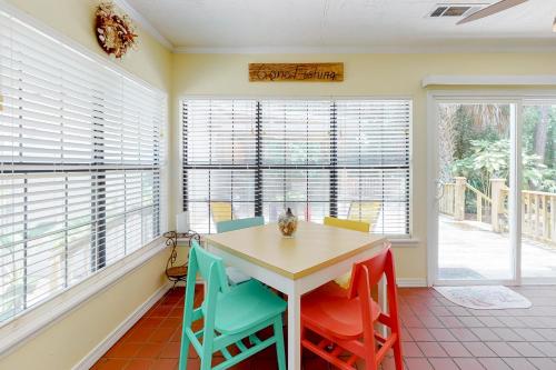 a dining room with a table and colorful chairs at Whispering Palms in Dauphin Island