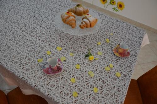 a table with a white table cloth with cakes and cups at Il Girasole del Centro Storico in Alcamo