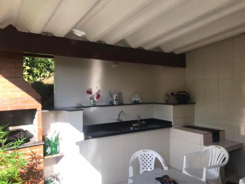 a kitchen with a sink and two white chairs at Tabarka Lodge in Nova Friburgo