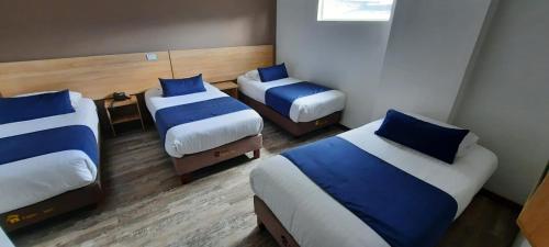 a room with three beds with blue pillows at HM HOTEL Expo Inn in Bogotá