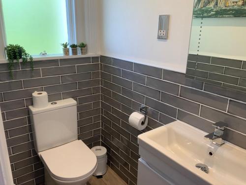 a bathroom with a white toilet and a sink at Promenade Apartment with own Beach Hut in Totland