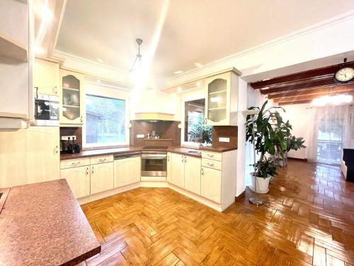 a large kitchen with white cabinets and a wooden floor at Holiday home with Jakuzzi and Sauna in Kisoroszi