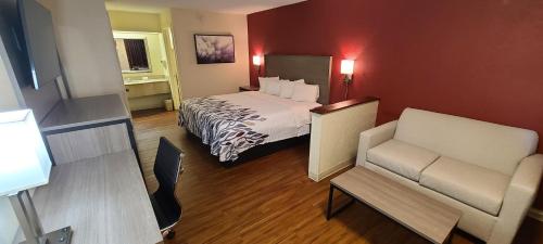 a hotel room with a bed and a chair at Red Roof Inn & Suites Cornelius - Lake Norman in Cornelius