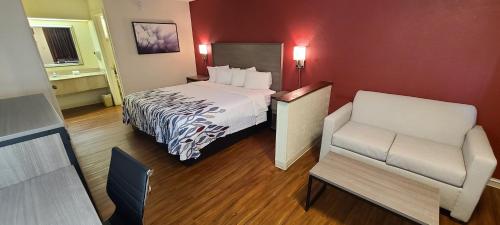 a hotel room with a bed and a chair at Red Roof Inn & Suites Cornelius - Lake Norman in Cornelius