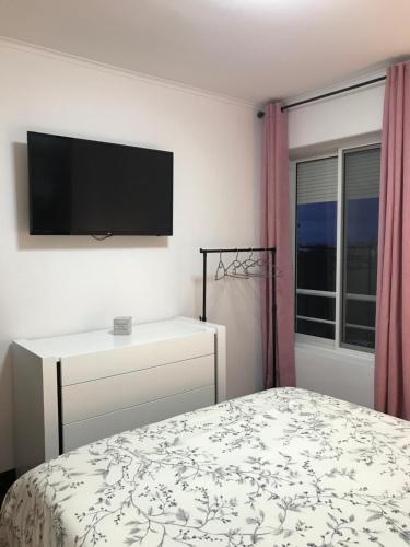 a bedroom with a bed and a flat screen tv at Sweet Home in Ponta Delgada