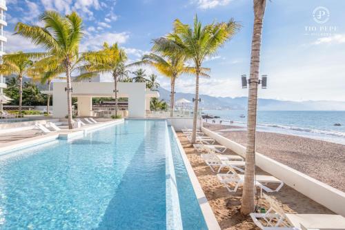 a swimming pool next to a beach with palm trees at Harbor Puerto Vallarta 2008 in Puerto Vallarta