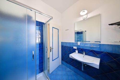 W wyłożonej niebieskimi kafelkami łazience znajduje się umywalka i prysznic. w obiekcie A' casa 'e Carmeniello w mieście Ischia