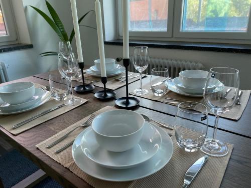 a wooden table with plates and wine glasses on it at Airport Apartment für 4 - Smart TV - Küche - eCharger in Hamburg