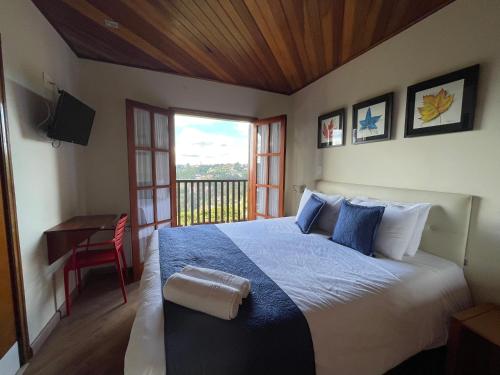 a bedroom with a bed and a desk and a window at Summit Suítes Hotel Campos do Jordão in Campos do Jordão