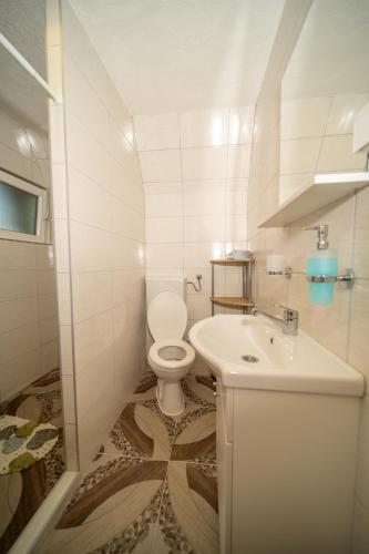 a white bathroom with a toilet and a sink at Pyramid Energy House in Visoko