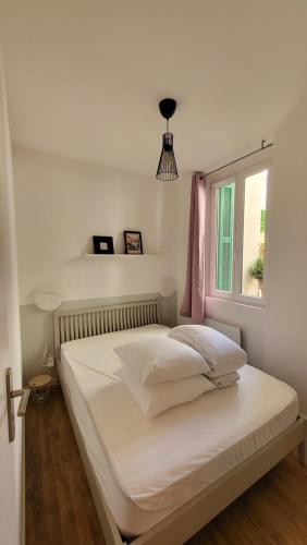 une chambre avec un lit avec des draps blancs et une fenêtre dans l'établissement Escapade à Lourdes dans beau T2 avec terrasse - Proche Gare et Centre ville, à Lourdes