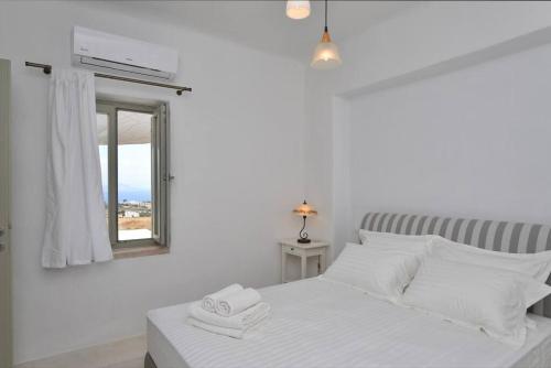 a white bedroom with a bed and a mirror at White House with Sea View in Ambelas