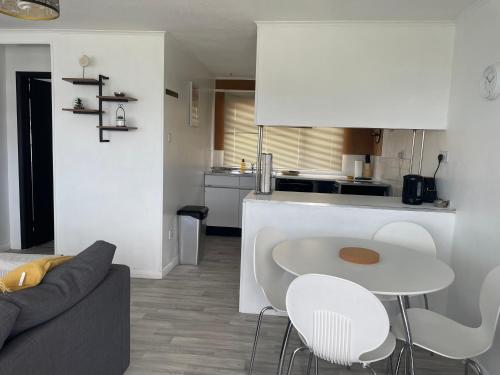 a kitchen and living room with a white table and chairs at Romney Sands Holiday Apartment in New Romney