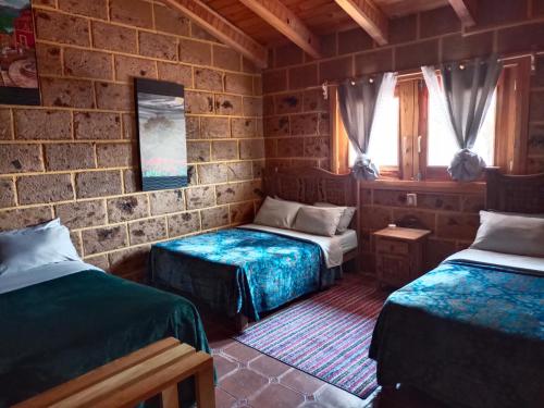 a bedroom with two beds and a brick wall at Cabaña el piñon en Ezequiel Montes in Ezequiel Montes