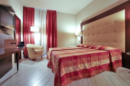 a hotel room with a bed and a chair at Hotel Touring in Fiorano Modenese