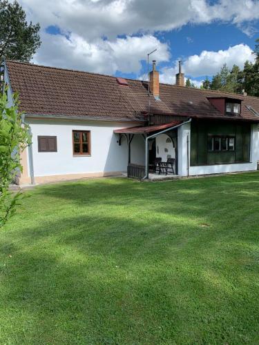 a white house with a large grass yard at Chalupa u rybníka in Libín
