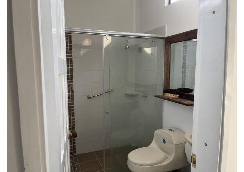 a bathroom with a toilet and a glass shower at Hotel Melgar Villa Valeria in Melgar