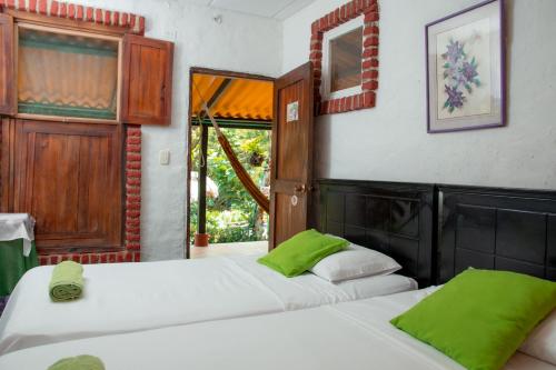 2 camas en una habitación con almohadas verdes en Entre Bosques Tayrona, en Los Naranjos