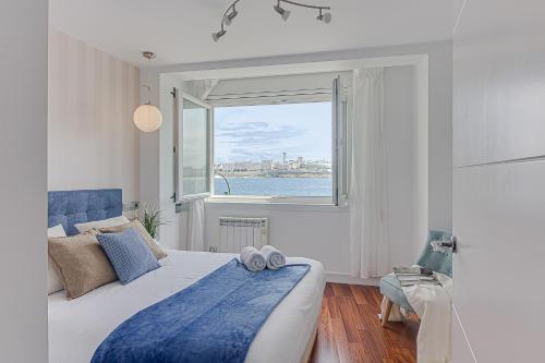 a bedroom with a bed and a large window at Riazor Ocean View Apartment in A Coruña