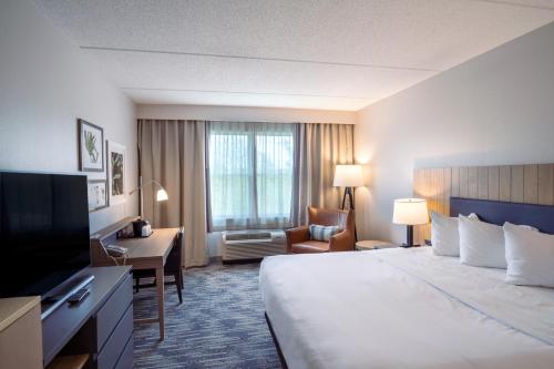 a hotel room with a large bed and a desk at Country Inn & Suites by Radisson, State College Penn State Area , PA in State College