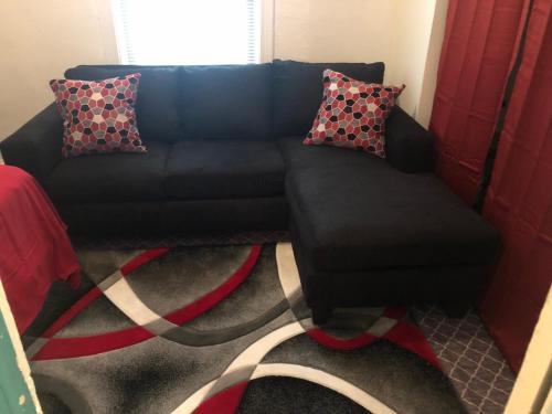 a black couch with pillows on a carpet at A Hidden Gem, approx 15 mins to downtown Chicago! in Chicago