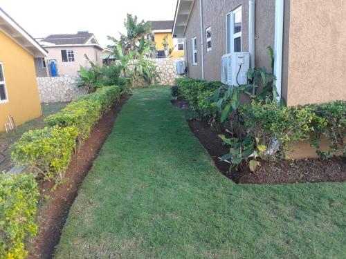 a yard with grass and bushes next to a building at Seaview Villa at Stonebrook Manor in Falmouth