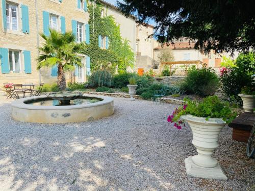 a garden with a fountain in the middle of a building at Aux Berges du Libre in Félines-Termenès