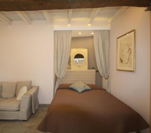 a bedroom with a bed and a couch and a mirror at Little Luxury Suite in Tremezzo
