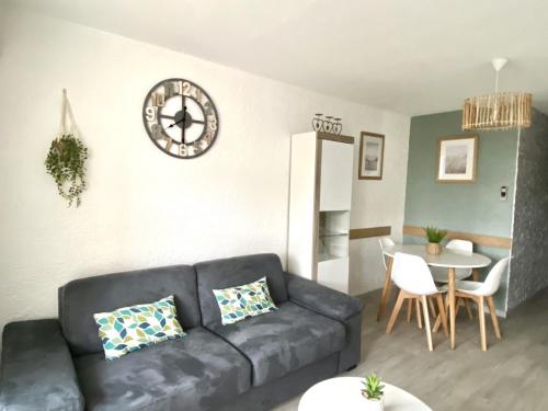 un salon avec un canapé et une horloge au mur dans l'établissement Superbe Apt, 250m plage du môle, clim, parking, au Cap d'Agde